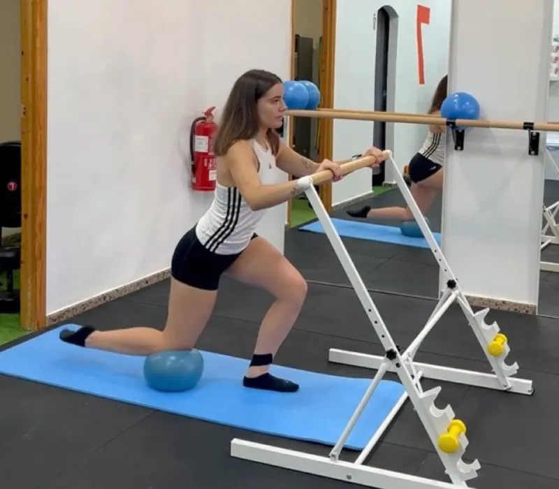 Alumna realizando un ejercicio de Barre con barra y pelota en la sala de Pilates y Barre de 7entrenamiento, Castalla